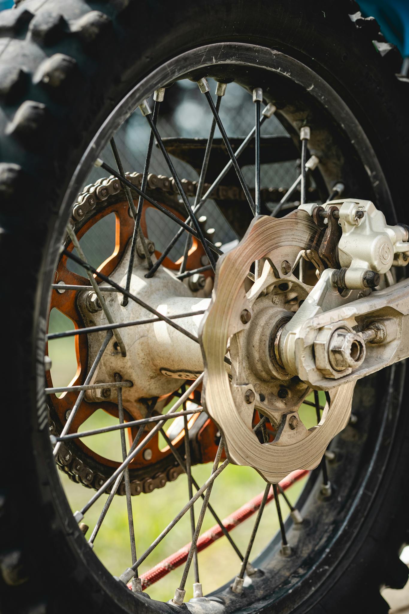 Detailed view of a dirt bike wheel showcasing the brake disc and tire in an outdoor setting.
