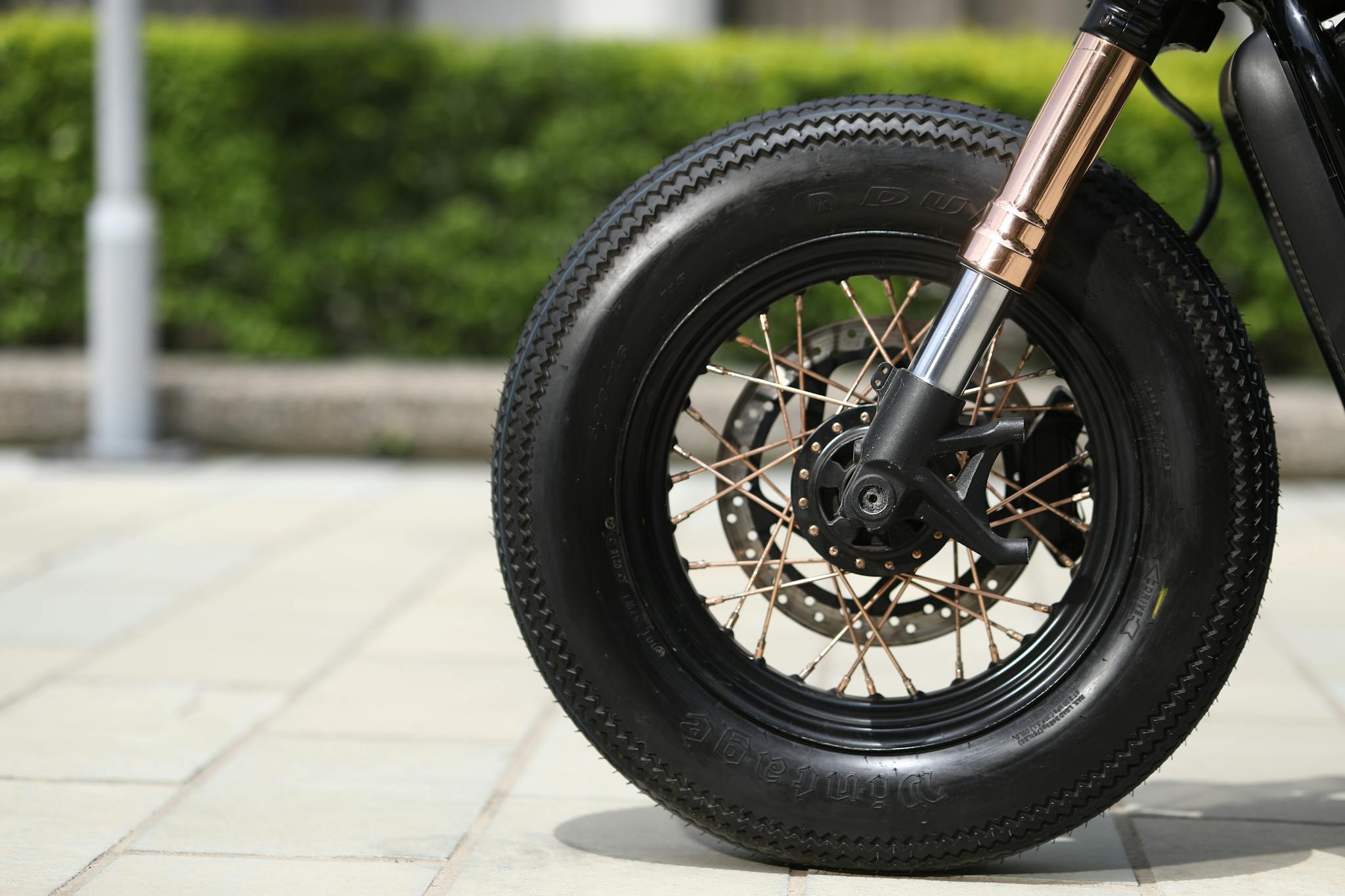 Detailed view of a motorcycle wheel with spoked tire in an outdoor setting.