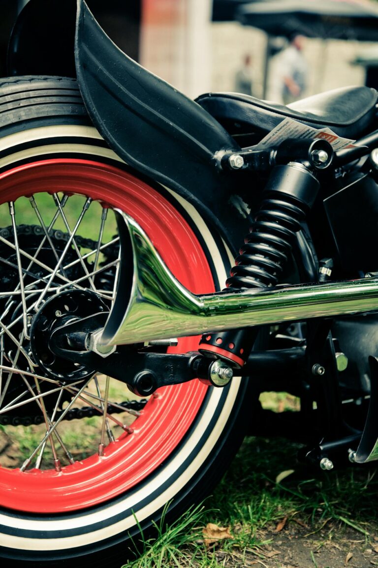 Detailed view of a retro motorcycle with vibrant red wheel rim and chrome exhaust.